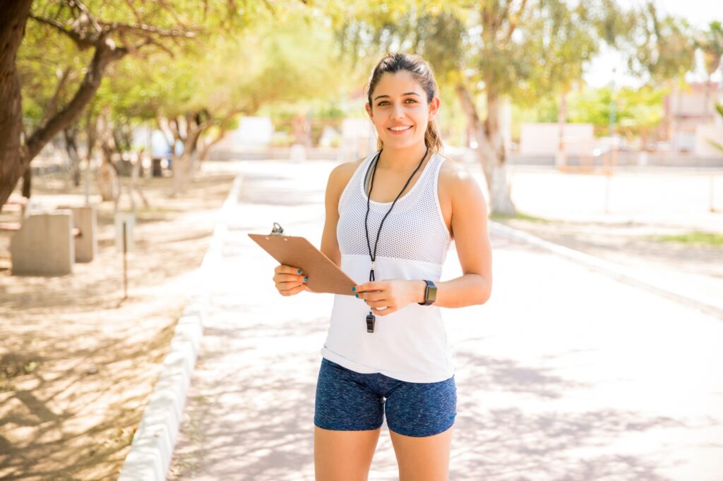 Female gym trainer at the park with clipboard